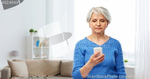 Image of senior woman using smartphone at home