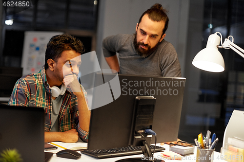 Image of creative team with computer working late at office