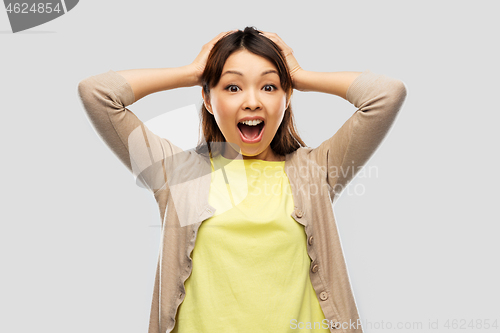 Image of happy asian woman holding to her head