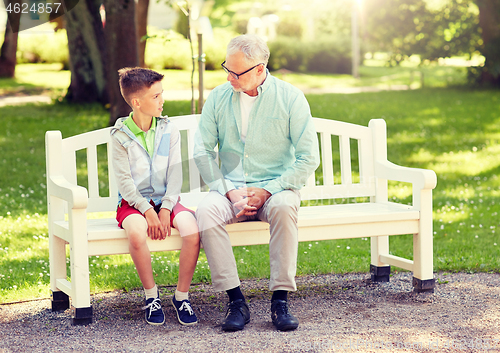 Image of grandfather and grandson talking at summer park