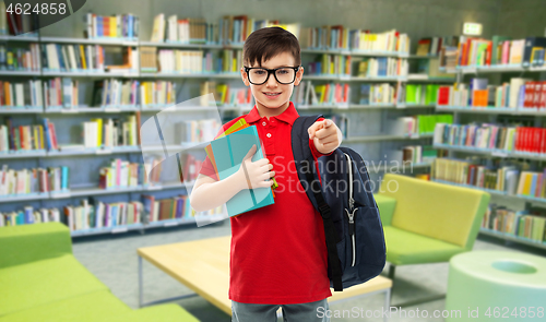 Image of smiling schoolboy in glasses with books at library