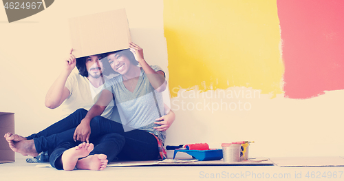 Image of young multiethnic couple playing with cardboard boxes