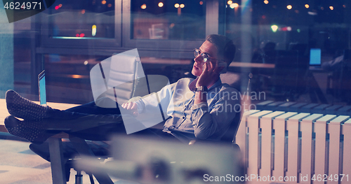 Image of businessman sitting with legs on desk at office