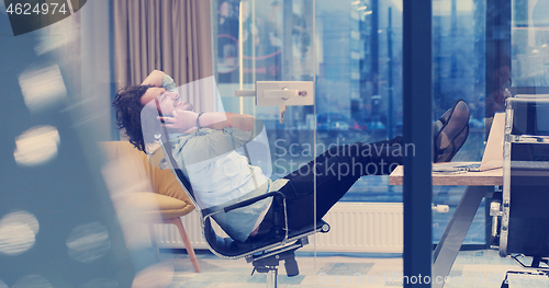 Image of businessman sitting with legs on desk