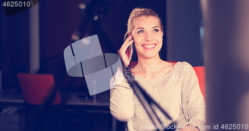 Image of woman using mobile phone in dark office