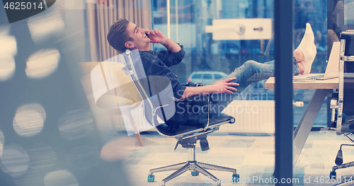 Image of businessman sitting with legs on desk