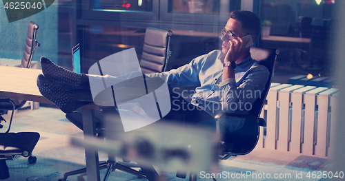 Image of businessman sitting with legs on desk at office