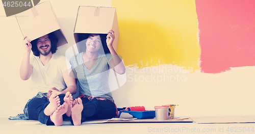 Image of young multiethnic couple playing with cardboard boxes