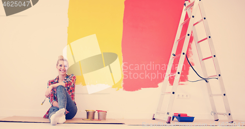 Image of young female painter sitting on floor