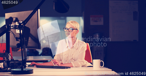 Image of woman working on computer in dark office