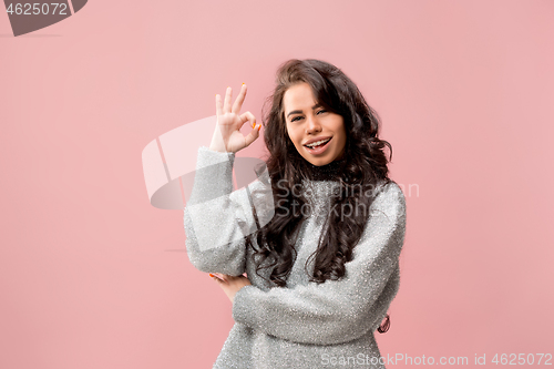 Image of The happy business woman standing and smiling against pink background.