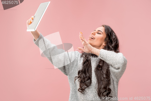 Image of Portrait of a confident casual girl looking at laptop isolated over pink background