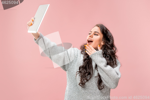 Image of Portrait of a confident casual girl looking at laptop isolated over pink background