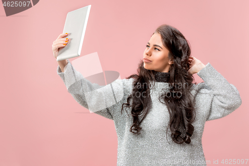 Image of Portrait of a confident casual girl looking at laptop isolated over pink background