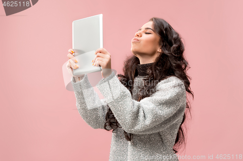 Image of Portrait of a confident casual girl looking at laptop isolated over pink background