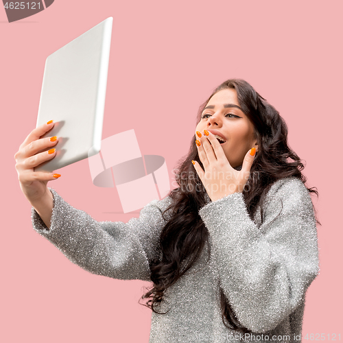 Image of Portrait of a confident casual girl looking at laptop isolated over pink background
