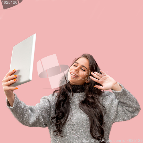 Image of Portrait of a confident casual girl looking at laptop isolated over pink background