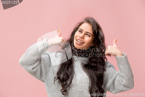 Image of The happy business woman standing and smiling against pink background.