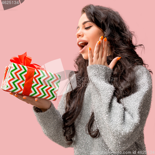 Image of Woman with big beautiful smile holding colorful gift box.