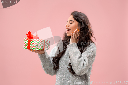 Image of Woman with big beautiful smile holding colorful gift box.