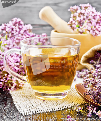 Image of Tea of oregano in cup with mortar on dark board