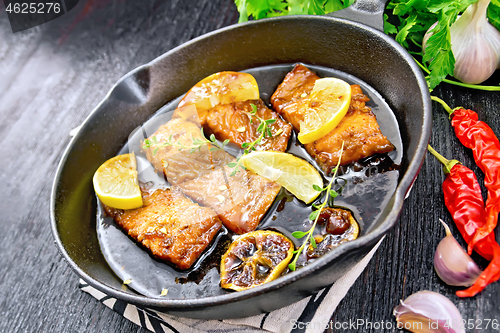 Image of Salmon with sauce in pan on dark board