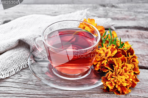 Image of Tea herbal of marigolds in glass cup on old board