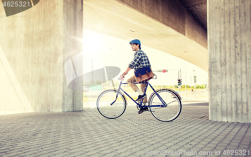 Image of young hipster man with bag riding fixed gear bike