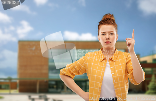 Image of red haired teenage girl with finger up over school