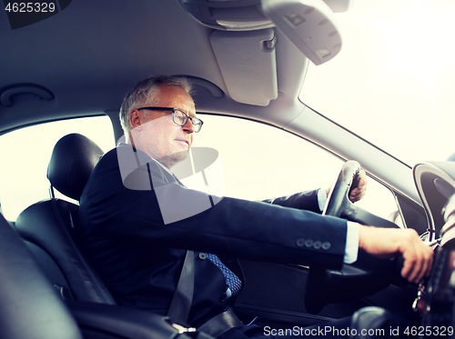 Image of happy senior businessman starting car and driving