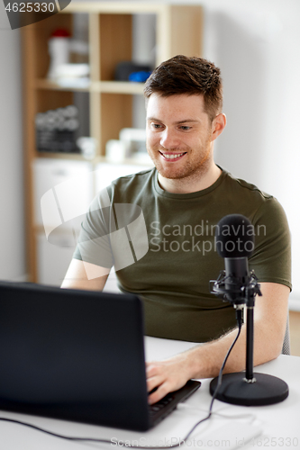 Image of man with laptop and microphone at home office
