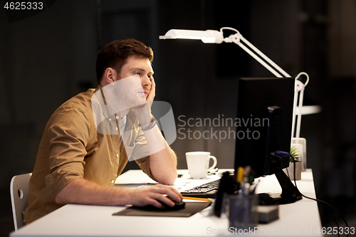 Image of tired or bored man working late at night office