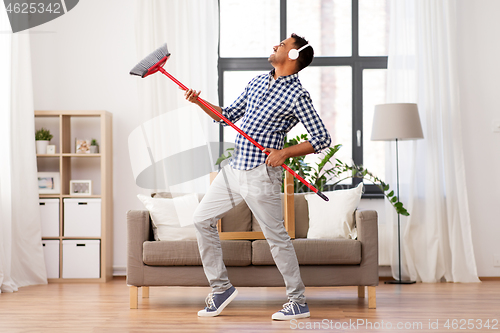 Image of man with broom cleaning and having fun at home