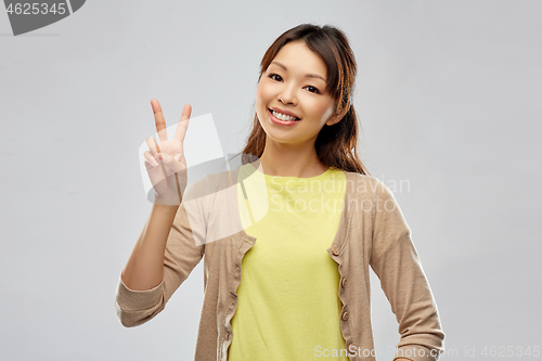 Image of happy asian woman showing peace