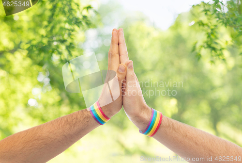 Image of hands with gay pride wristbands make high five