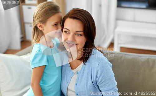 Image of daughter whispering secret to mother at home