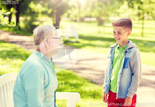 Image of grandfather and grandson talking at summer park