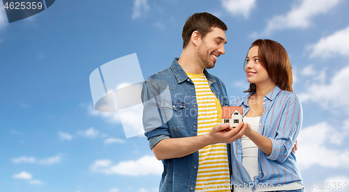 Image of smiling couple holding house model