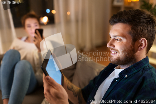 Image of couple with tablet computer and smartphone at home