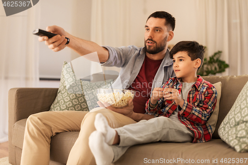 Image of father and son with popcorn watching tv at home