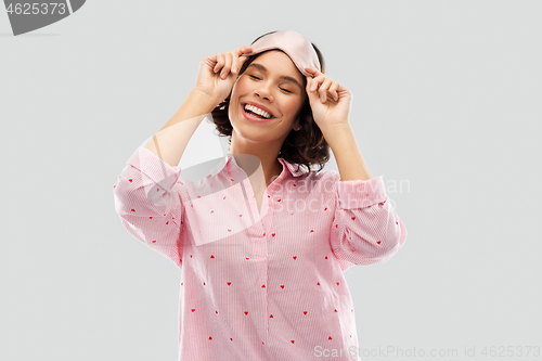 Image of happy young woman in pajama and eye sleeping mask