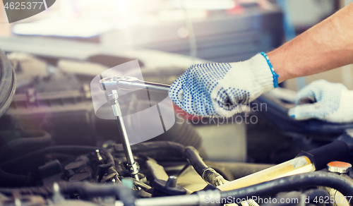 Image of mechanic man with wrench repairing car at workshop