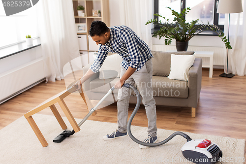 Image of indian man with vacuum cleaner at home