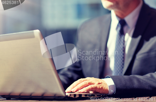 Image of senior businessman with laptop at outdoor cafe