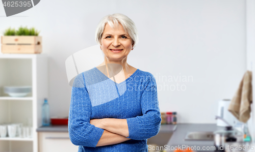 Image of smiling senior woman in blue sweater at kitchen