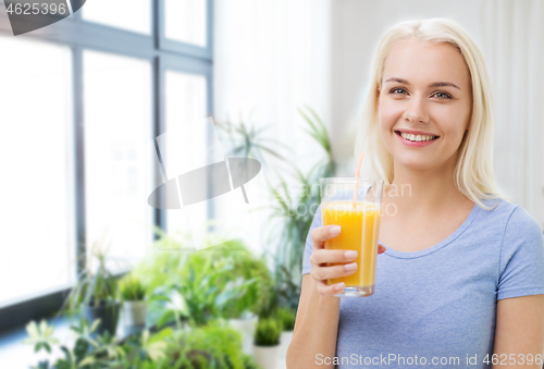 Image of smiling woman drinking orange juice at home