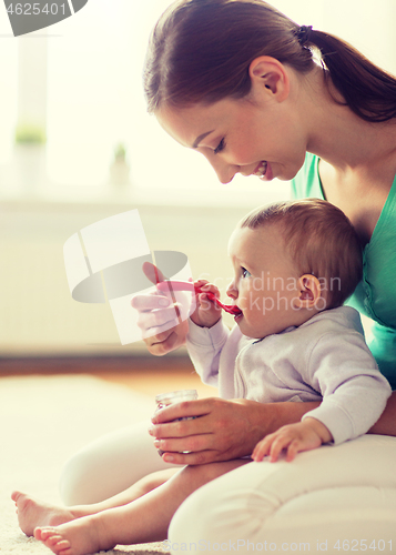 Image of happy mother with spoon feeding baby at home