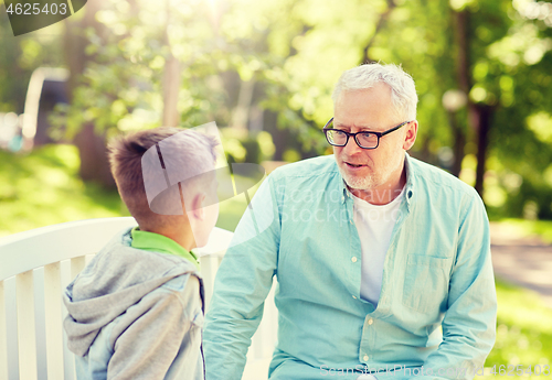 Image of grandfather and grandson talking at summer park