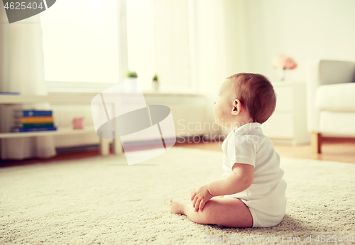 Image of happy baby boy or girl sitting on floor at home