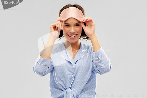 Image of happy young woman in pajama and eye sleeping mask